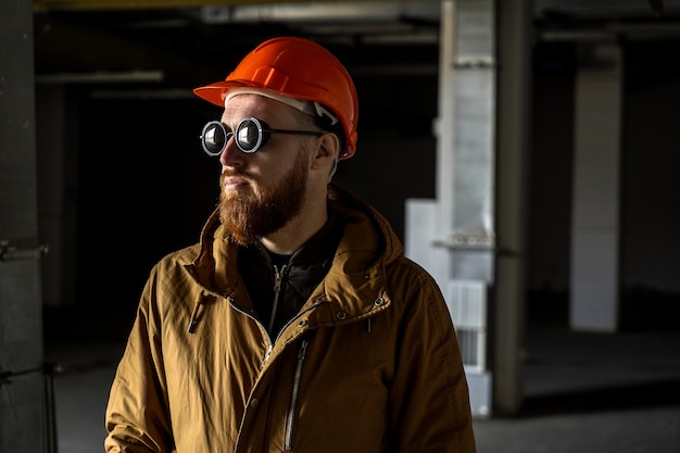 Man in een helm en zonnebril in een donkere kamer, kijkt weg