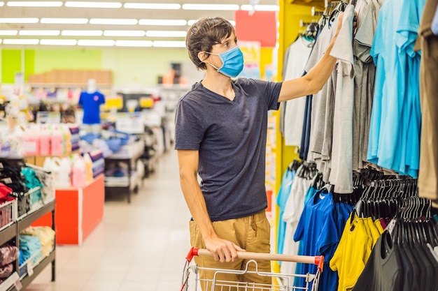 Man in een kledingwinkel met een medisch masker vanwege een coronovirus quarantaine is voorbij nu kun je naar de kledingwinkel