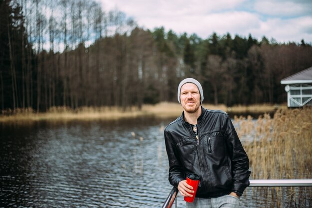 man in een leren jas staat aan het meer