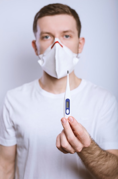 Man in een medisch masker houdt een thermometer