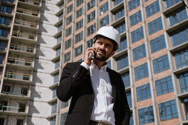 Man in een pak en beschermende helm praten aan de telefoon