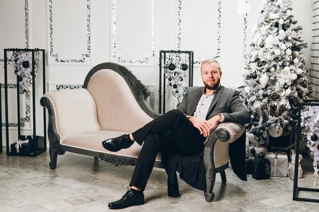 Man in een pak vormt in de buurt van de kerstboom