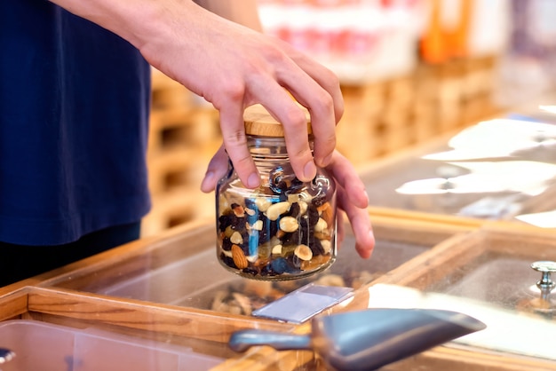 Man in een supermarkt met pot met noten