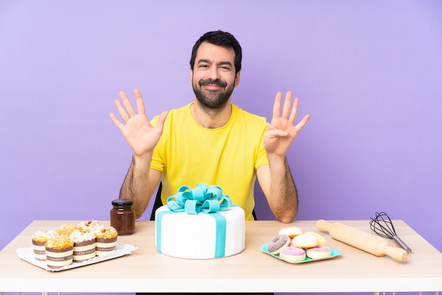 Man in een tafel met een grote taart die negen telt met vingers