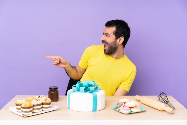 Man in een tafel met een grote taart wijzende vinger naar de zijkant