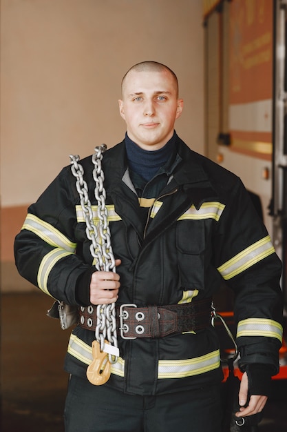 Man in een vuuruniform. Brandweerman dichtbij auto. Man in garage