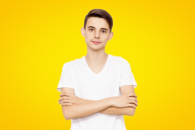 Man in een wit T-shirt gevouwen handen geïsoleerd op een gele achtergrond, vriendelijke man