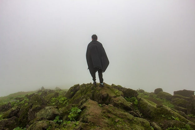 Man in een zwarte cape die voor een afgrond staat kijkt naar de lucht