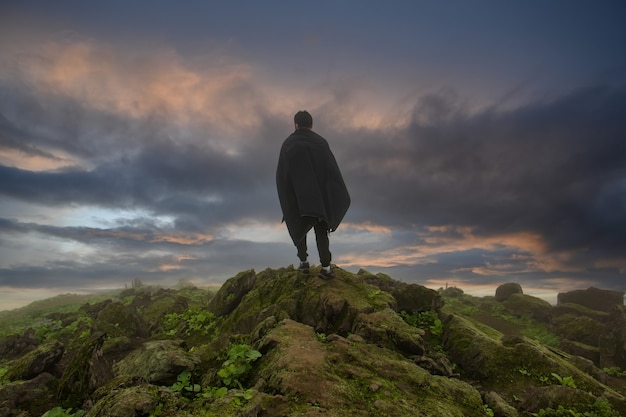 Man in een zwarte cape die voor een afgrond staat kijkt naar de lucht