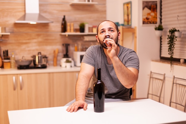 Man in eenzaamheid en frustratie die een fles wijn drinkt en een kater krijgt. Ongelukkige persoon ziekte en angst gevoel uitgeput met alcoholisme problemen.