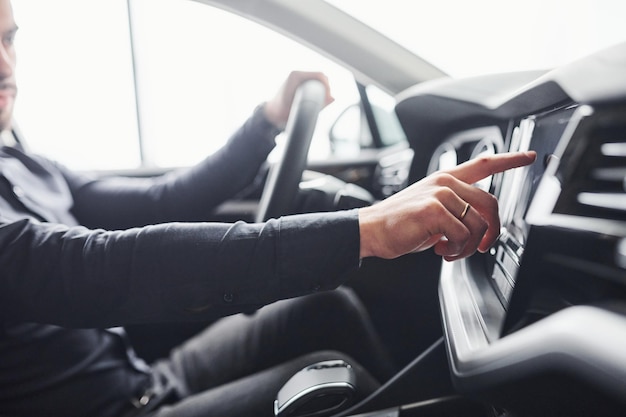 Man in elegante kleding zittend in gloednieuwe dure auto.