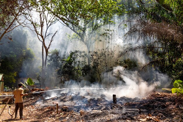 man in gaasverband en brandslang die vuur probeert te blussen in het bos Vuur en rook in de jungle