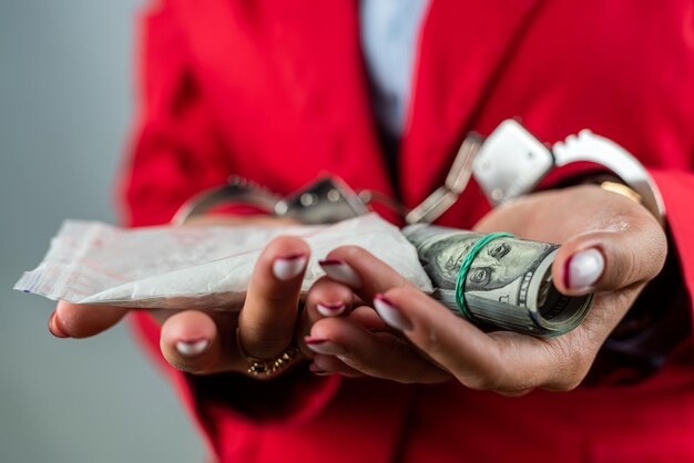 Фото Человек в наручниках с деньгами и белым пакетом пороха в руках концепция наказания за наркотики
