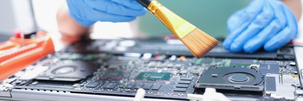 Man in handschoenen met een penseel maakt laptoponderdelen schoon