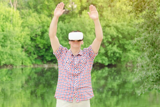 Foto man in helm van virtual reality tegen de natuur. handen omhoog