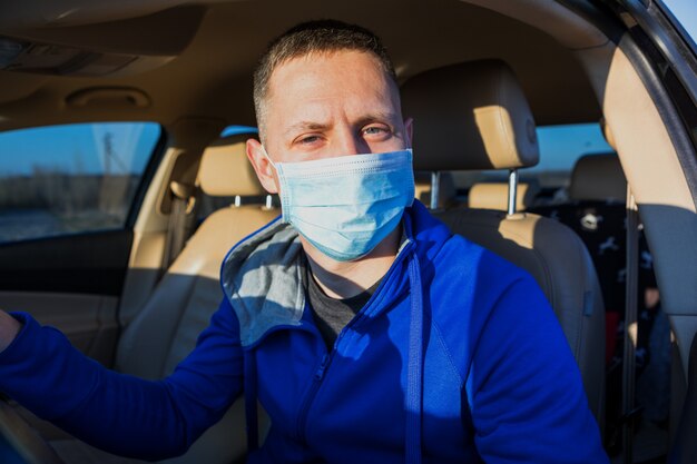 Man in het medische masker besturen van een auto