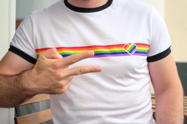 Man in het t-shirt met lgbt-vlag toont teken vrede homo- en lesbische rechten concept