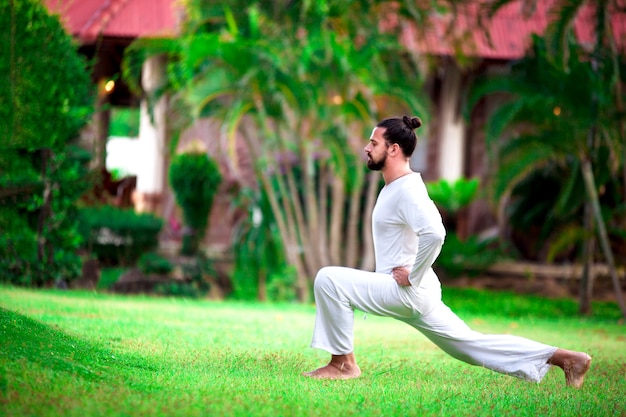 Man in het wit die yoga doet in de tropische jungle