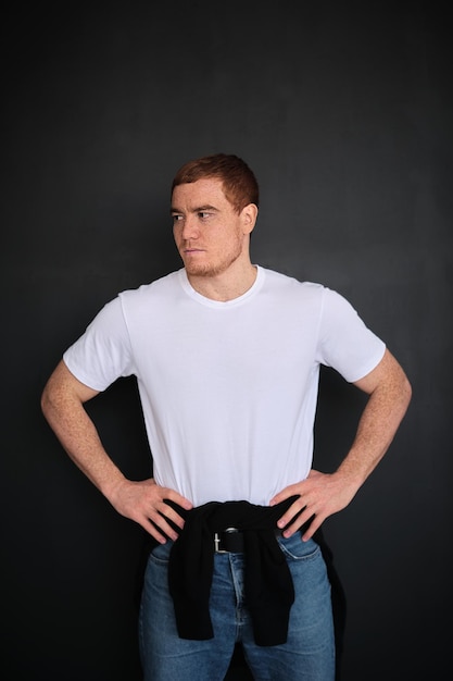 Man in het witte T-shirt met ruimte om kopie te plakken op de zwarte muur achtergrond