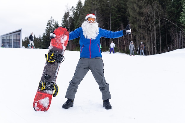 Man in kerstman hoed met een snowboard in een skiresort.