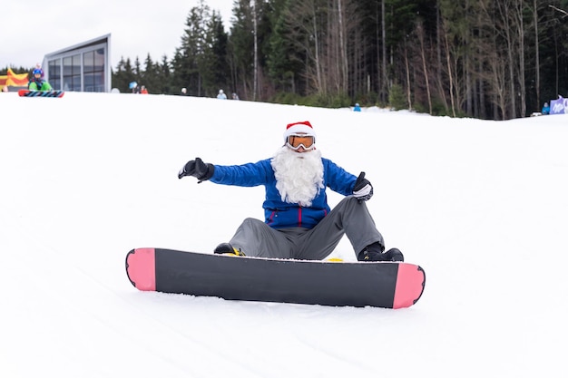 Man in kerstman hoed met een snowboard in een skiresort.