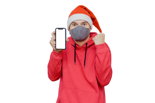 Man in kerstmuts met een mobiele telefoon en een masker als een symbool van kerstviering 2020 in pandemische tijden.