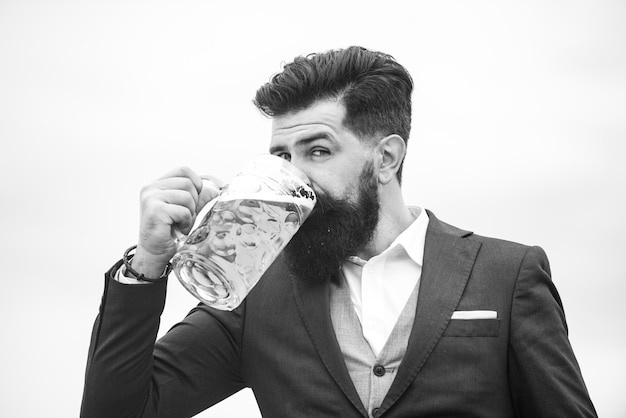 Man in klassiek pak die bier met baard drinkt in klassieke outfit ziet er gelukkig en tevreden uit o