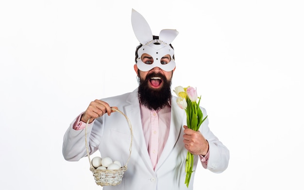 Man in konijn masker met Pasen mand eieren en bloemen.