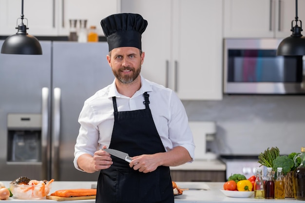 Man in kookschort en chef-kokhoed in moderne keuken die viszalm bereidt knappe man kookt vers