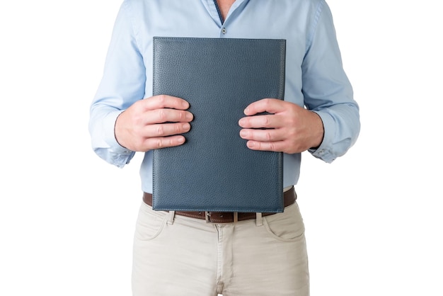 Man in lichtblauw shirt en beige broek met een map gesloten met beide handen op een witte achtergrond