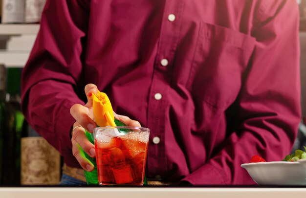 Man in magenta hemd bereidt kleurrijke cocktail voor