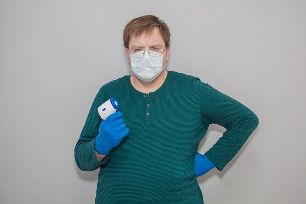 Man in masker en handschoenen met een thermometer tegen coronavirus