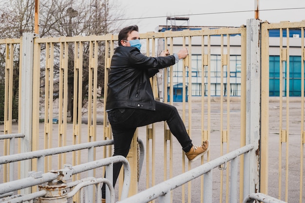 Man in medische masker klimmen over het hek, vluchtelingenconcept, coronavirus quarantaine.