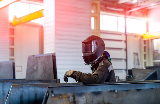 Man in metalen fabriekshelm aan het werk professioneel lassen van metalen