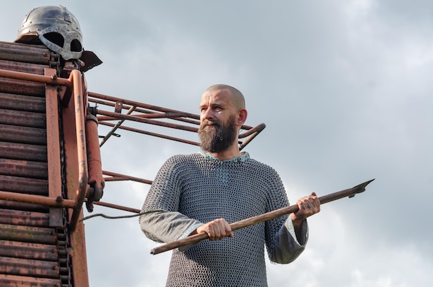 Man in middeleeuwse kleding op een zomerveld Vikingpantser Metalen helm en maliënkolder