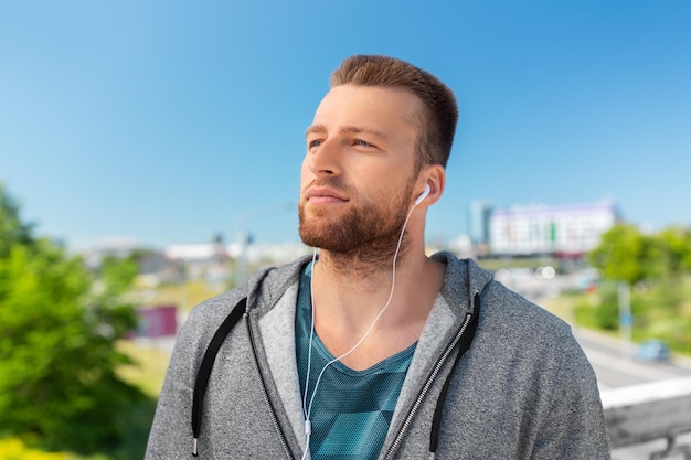 man in oordopjes die buiten naar muziek luistert