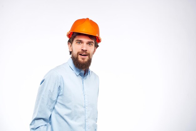 Фото Человек в оранжевой каске, промышленный инженер, работает на профессиональном светлом фоне