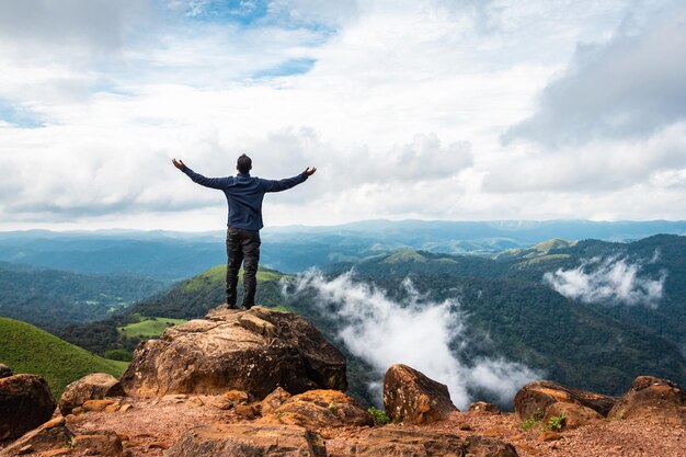 Foto man in overwinningspose op de top van de berg in de ochtend