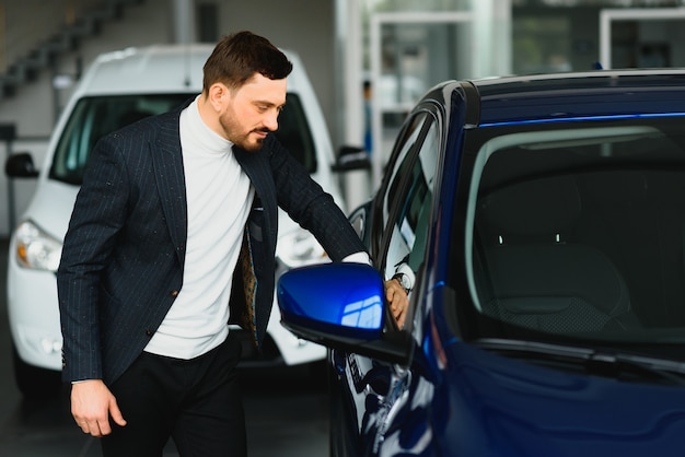 Man in pak die een nieuwe blauwe auto koopt