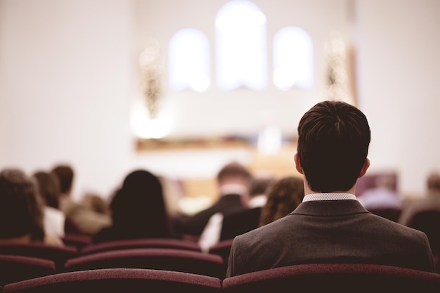 Man in pak en andere mensen die in een kerk zitten