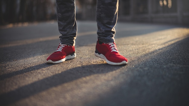 Man in rode sport sneakers loopt op een zonnige dag door de straat