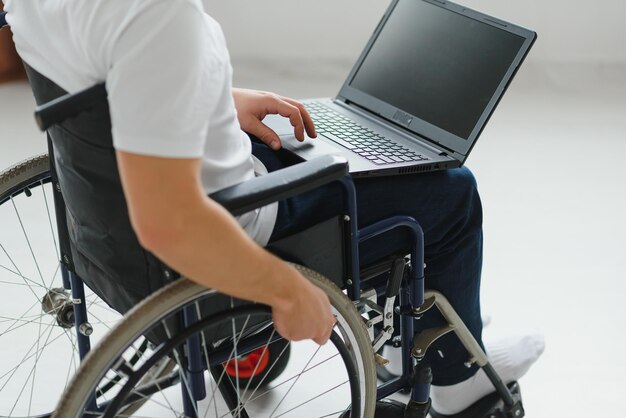 Man in rolstoel die aan laptop in woonkamer werkt