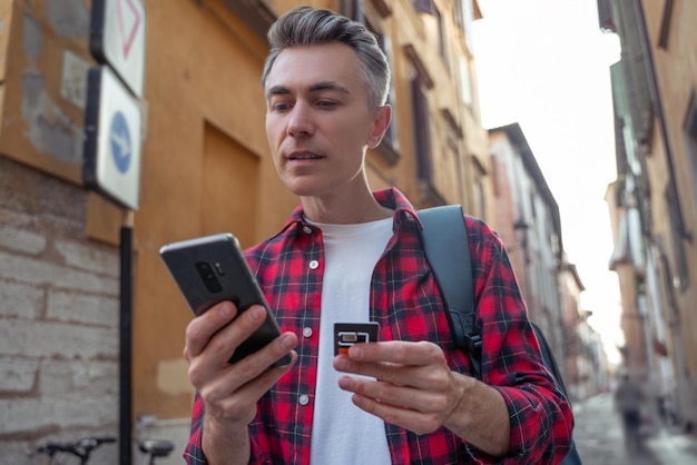 Man in rood geruit overhemd met een gadget in handen