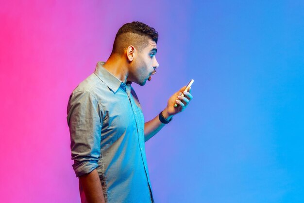 Man in shirt die online service op mobiele telefoon gebruikt en verbazing uitdrukt