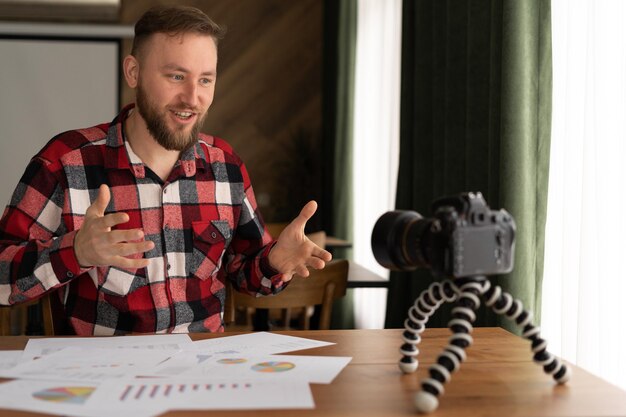 Foto man in shirt toont statistieken grafiek pad maken promo videoblog of fotosessie in camcorder op statief vlogger selfie verkoop oplossing of financiën adviseur management informatie marketing lezing