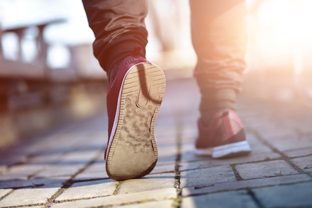 Man in sneakers loopt op een zonnige dag over straat