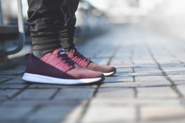 Man in sneakers loopt op een zonnige dag over straat