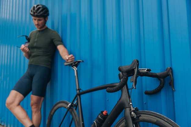 Man in sportkleding en helm die buiten staat met fiets