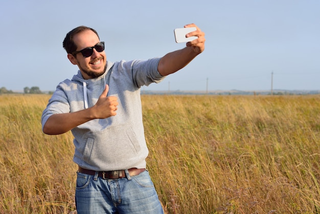 写真 サングラスの男がフィールドでselfieを撮影します。