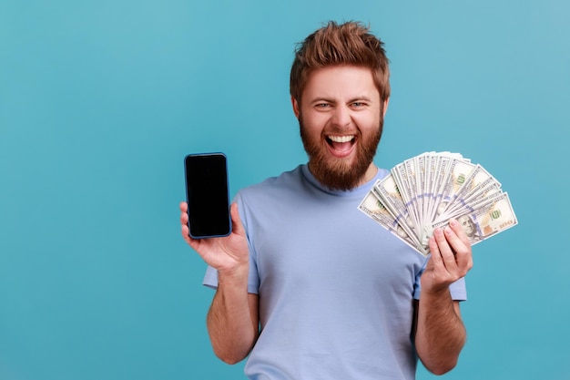 Man in t-shirt met dollarbiljetten en mobiele telefoon met een leeg scherm online weddenschappen winnen